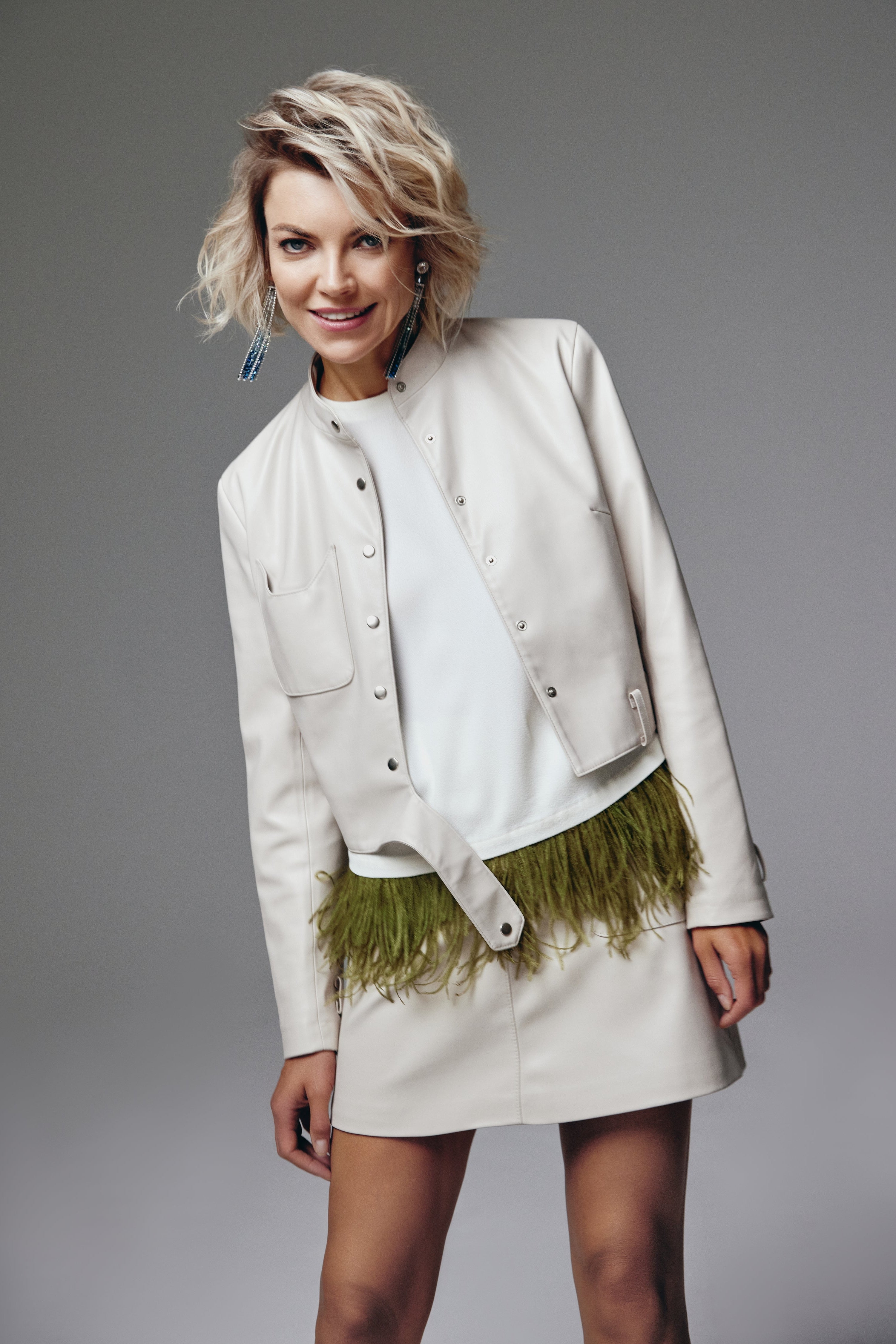 Woman wearing White Catty Jacket from Mimaussy Paris, front view against gray studio background with green feather details