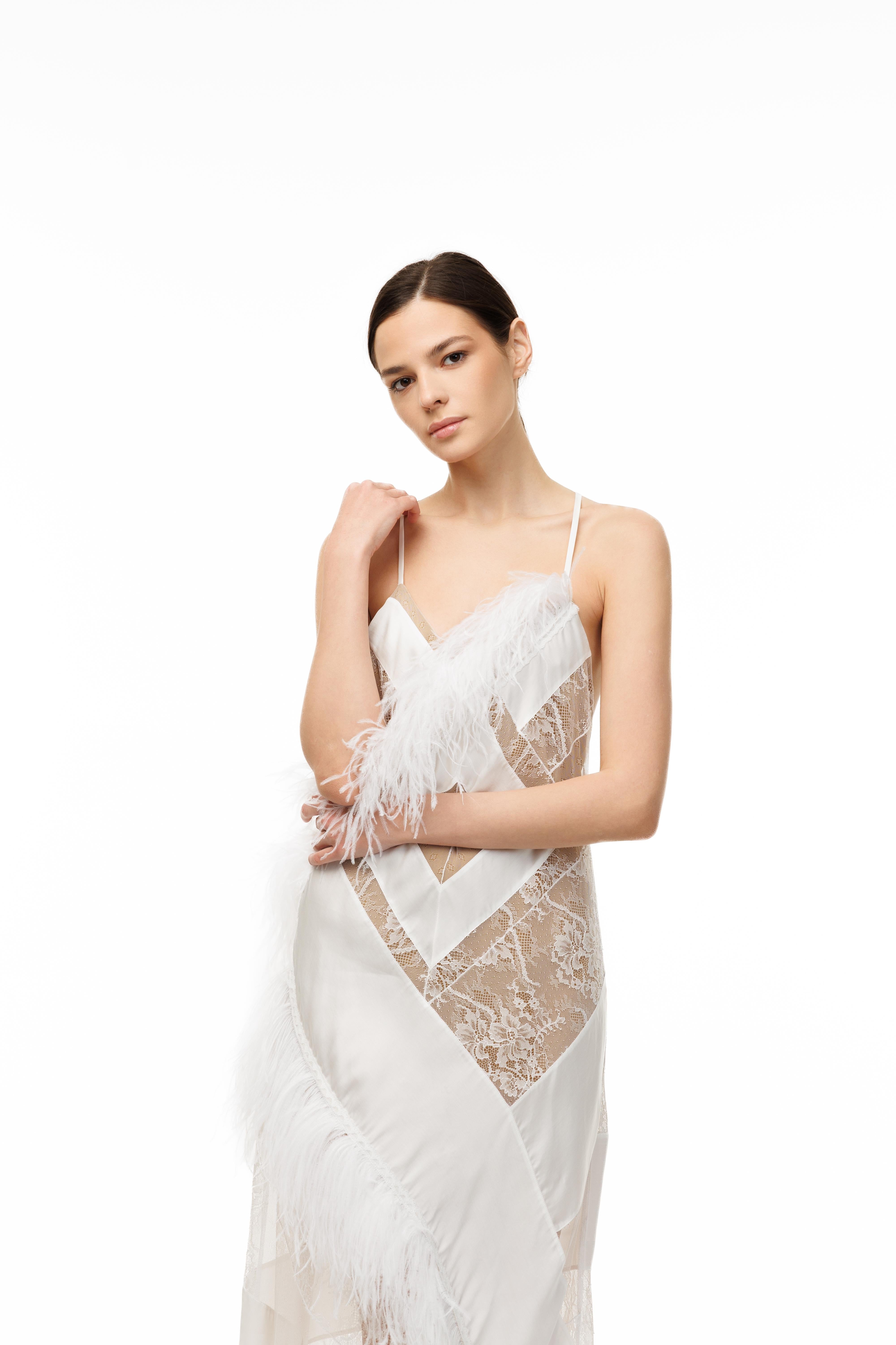 Woman wearing a white lace dress with feather details on a white background