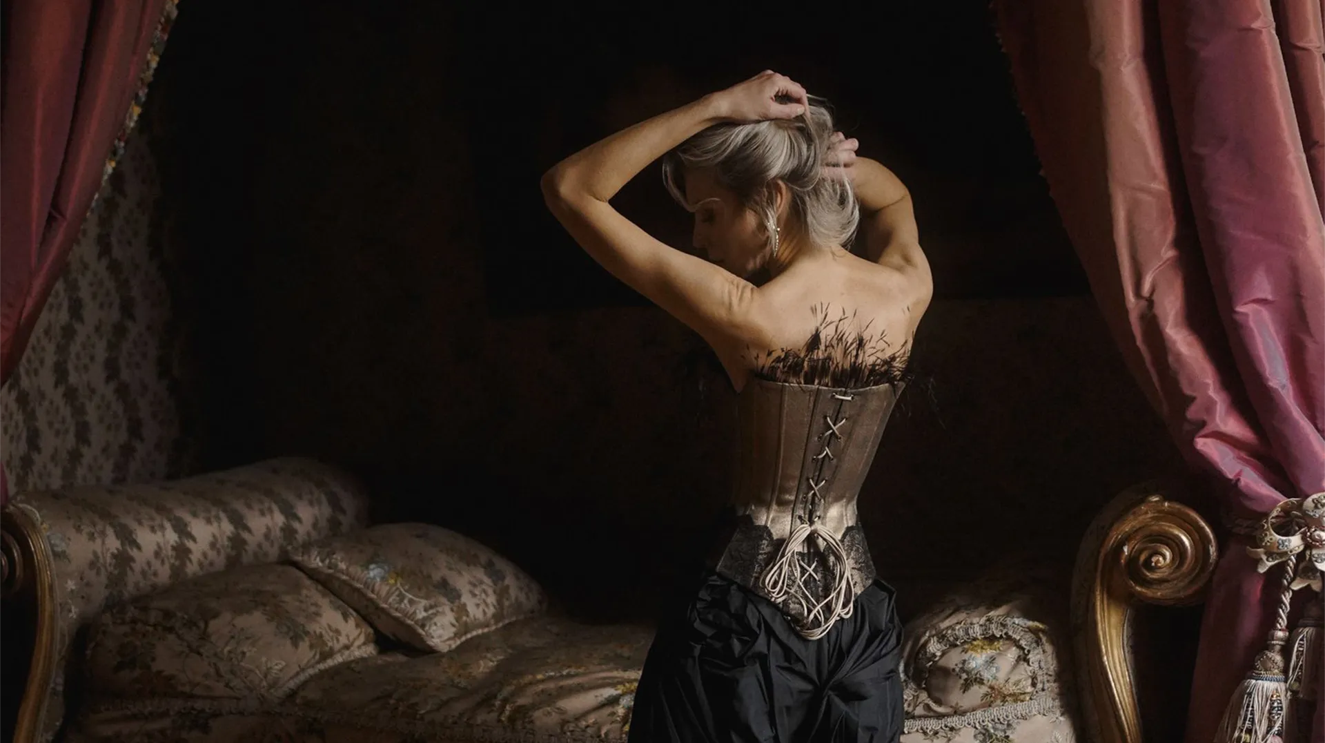 Lady wearing a Mimaussy Gold denim corset in a dimly lit room with ornate furniture.